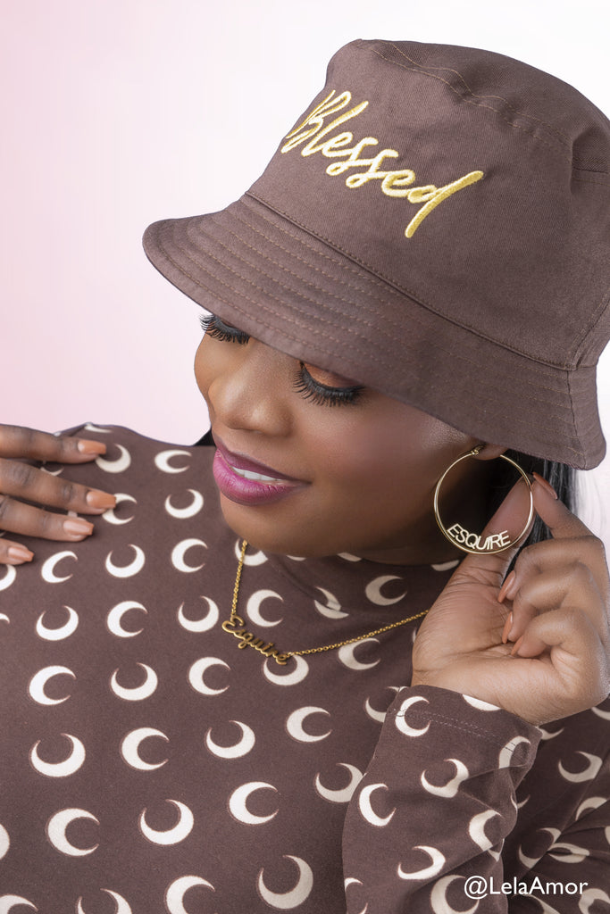 Woman wearing brown bucket hat and gold Esquire hoop earrings and gold esquire necklace